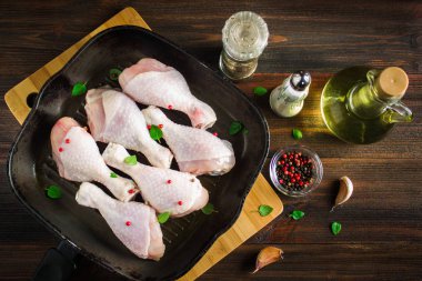 Ahşap bir masa üzerinde bir tavada çiğ tavuk budu. Et yemek pişirmek için malzemeler. Üstten Görünüm.