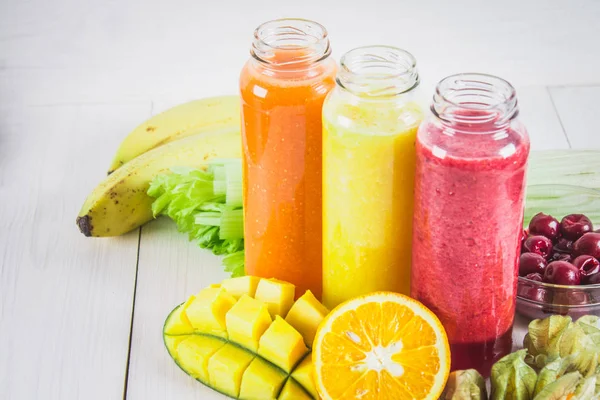 Multicolored smoothies in bottles of mango, orange, banana, cele