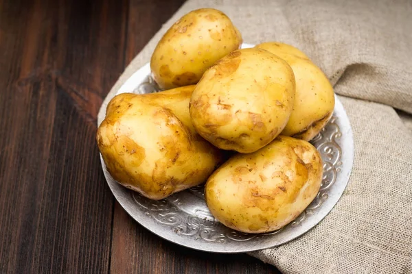 Çiğ patates kahverengi ahşap arka plan üzerinde.