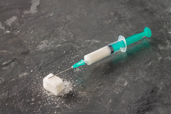 Sugar in a syringe. Conceptual depiction of dependence on the sweet. Sugar is a drug. Injection of sweets.