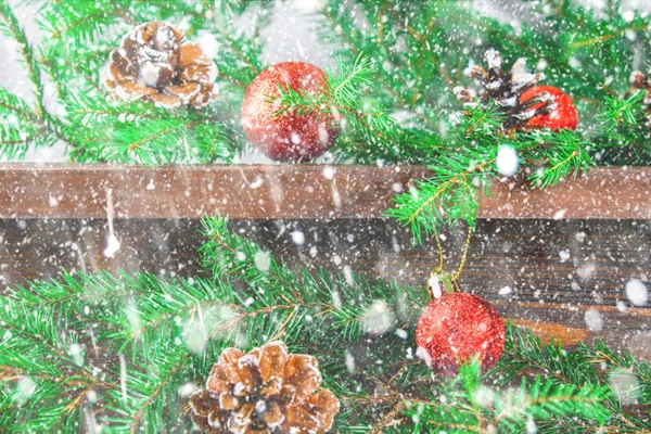 Bolas de Natal vermelho e cones estão em uma prateleira marrom de madeira cercada por ramos de abeto . — Fotografia de Stock