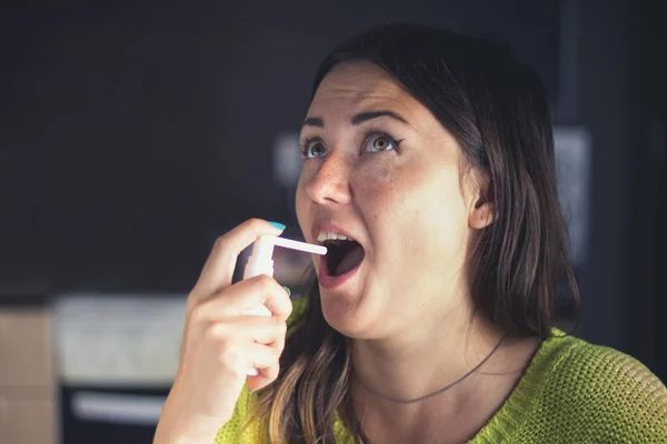 Het meisje spatten in haar mond met een spray van de pijn in haar keel. Behandeling van verkoudheden, griep. — Stockfoto