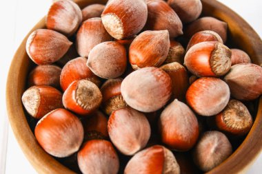 Beyaz ahşap bir masa üzerinde bir ahşap kase fındık fındık. Superfood.