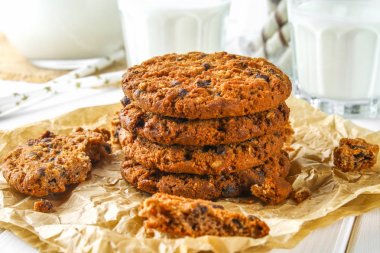 Ev yapımı yulaf ezmeli kurabiye. Bir parşömen kağıt arka planda. Ahşap beyaz masa üzerinde süt.