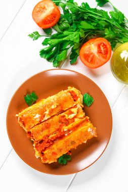 Geleneksel İtalyan makarna makarna. Pişmiş tüpler ile kıyma Beyaz ahşap bir masa üzerine Beşamel sos ve parmesan peyniri ile doldurulmuş.