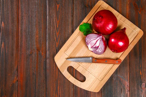 Fresh red onions and chopped slices on a wooden table. Top view. — Stock Photo, Image