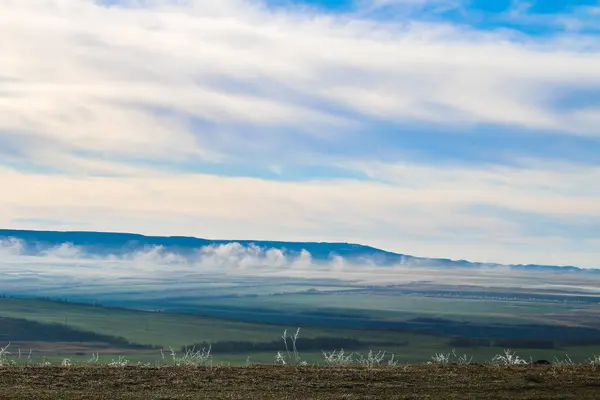 Erba in gelo dopo le gelate contro il cielo blu, campi e montagne . — Foto Stock