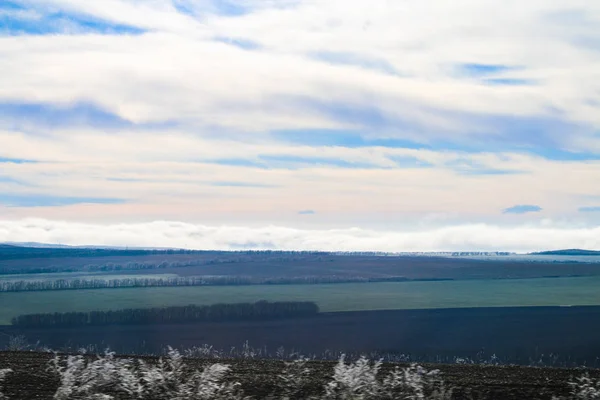 Erba in gelo dopo le gelate contro il cielo blu, campi e montagne . — Foto Stock