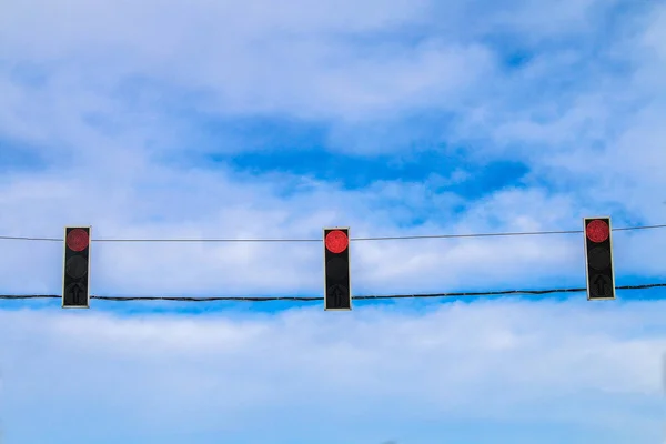 Três semáforos vermelhos pairam sobre a estrada contra o céu azul. Sinal de proibição . — Fotografia de Stock
