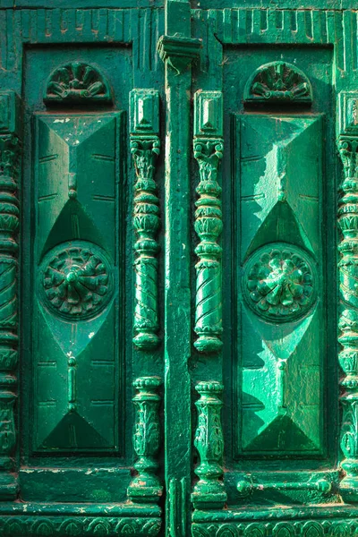 Un'antica porta in legno verde vintage con elementi intagliati in una giornata di sole . — Foto Stock