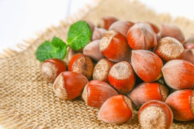 Beyaz ahşap bir masa üzerinde çul üzerinde dağınık ceviz fındık.