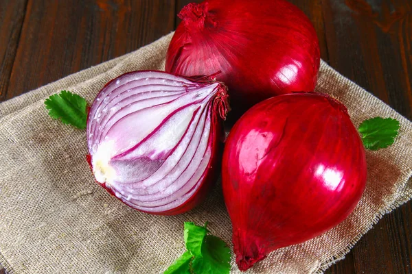 Fresh red onions and chopped slices on a wooden table. — Stock Photo, Image