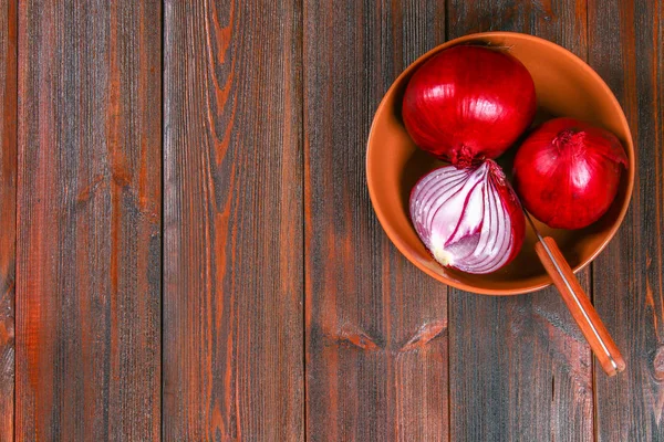 Čerstvé červené cibuli a nakrájené plátky na dřevěný stůl. Pohled shora. — Stock fotografie