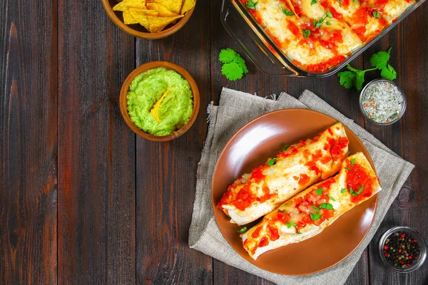 Zelfgemaakte kip enchiladas in schotel op houten tafel. Bovenaanzicht. — Stockfoto