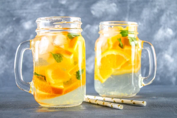 stock image Orange detox water in mason jars on a gray concrete background. Healthy food, drinks.