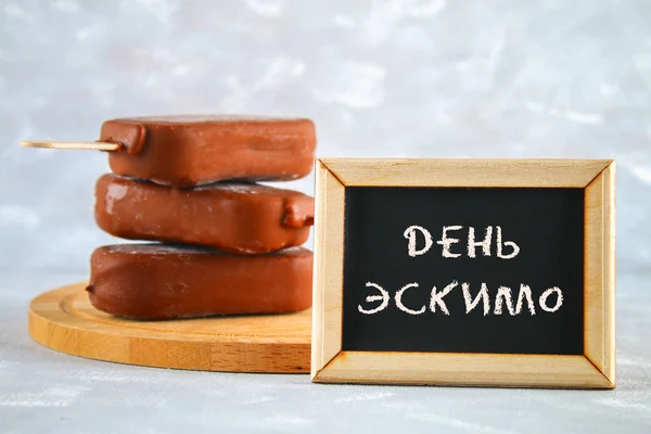 Ice cream eskimo pie on a stick with the text in Russian - Day eskimo pie. — Stock Photo, Image