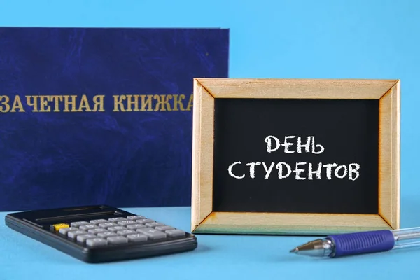 A blue book with an inscription in Russian - a student's record book. Pen, calculator on a blue background. Inscription in Russian - Students Day. — Stock Photo, Image