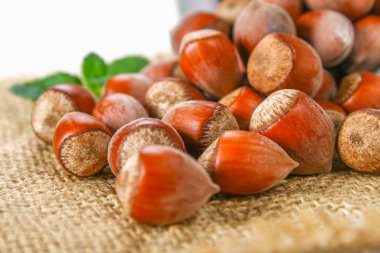 Beyaz ahşap bir masa üzerinde çul üzerinde dağınık ceviz fındık.