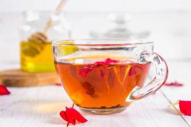 Bir fincan çay, bal ve bir kavanoz siyah bir bitki çiçek çayı ile bir banka beyaz ahşap bir masa üzerinde arka planda.