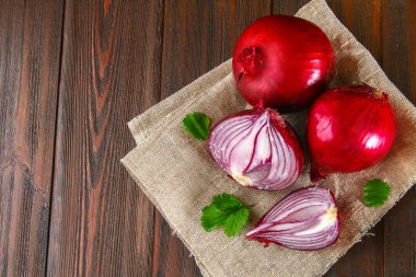 Taze kırmızı soğan ve doğranmış dilimleri ahşap bir masa üzerinde.