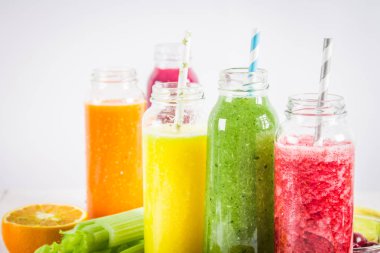 Mango, portakal, muz, kereviz, çilek, ahşap bir masa üzerinde şişelerde çok renkli smoothies.