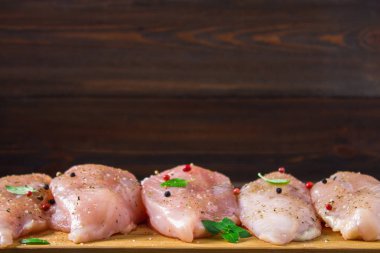 Çiğ tavuk fileto kesme tahtası ahşap bir masa arka planı. Et yemek pişirmek için malzemeler. Bir yazıt için boş yer. Kopyalama alanı.