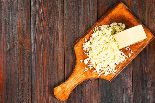 Porzione di formaggio Cheddar grattugiato su tavola di legno rustico . — Foto Stock