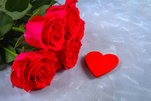 Ροζ τριαντάφυλλα με κόκκινα κεριά σε σχήμα καρδιάς σε γκρι φόντο. Πρότυπο για 8 Μαρτίου, ημέρα της μητέρας, ημέρα του Αγίου Βαλεντίνου. — Φωτογραφία Αρχείου