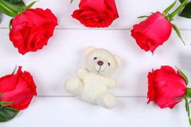 Beyaz ayıcık pembe Gül Beyaz ahşap bir masa üzerinde çevrili. Şablon için 8 Mart, anneler günü, Sevgililer günü.