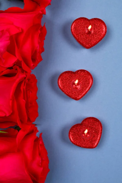Roze rozen met rode kaarsen in de vorm van een hart op een grijze achtergrond. Sjabloon voor 8 maart, Mother's Day, Valentijnsdag. — Stockfoto