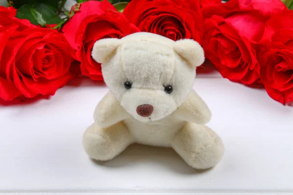 Urso de pelúcia branco cercado por rosas cor-de-rosa em uma mesa de madeira branca. Modelo para 8 de março, Dia das Mães, Dia dos Namorados . — Fotografia de Stock