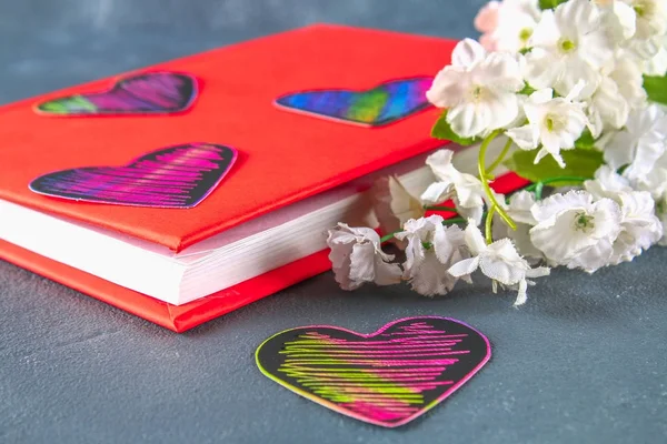 Черные и розовые сердца на книге в красной обложке и цветы на сером бетонном фоне. Концепция Дня Святого Валентина. Символ любви . — стоковое фото