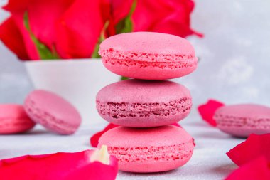 Pembe ve mor macaroons pembe ve beyaz çiçekler tarafından çevrili gri bir tablo.