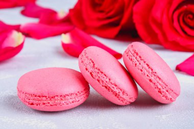 Pembe ve mor macaroons pembe ve beyaz çiçekler tarafından çevrili gri bir tablo.