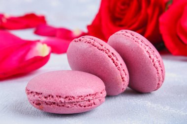 Pembe ve mor macaroons pembe ve beyaz çiçekler tarafından çevrili gri bir tablo.