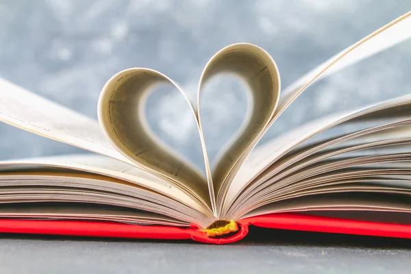 De bladzijden van het boek in de rode kaft zijn gemaakt in de vorm van een hart. Het concept van Valentijnsdag. — Stockfoto