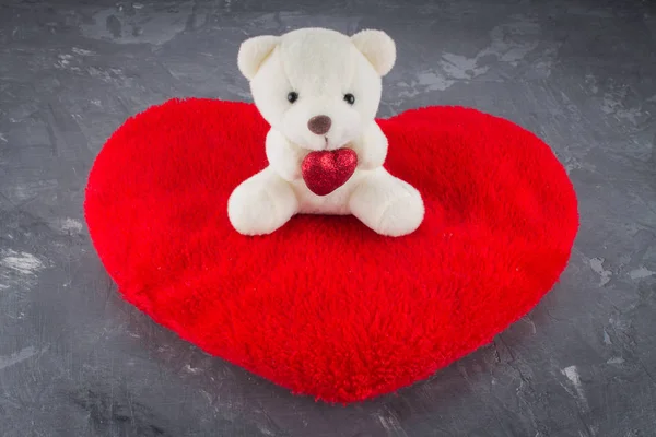 White toy teddy bear with heart on a gray background. The symbol — Stock Photo, Image