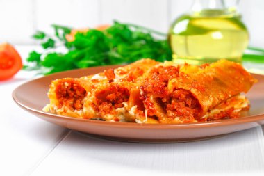 Geleneksel İtalyan makarna makarna. Pişmiş tüpler ile kıyma Beyaz ahşap bir masa üzerine Beşamel sos ve parmesan peyniri ile doldurulmuş.