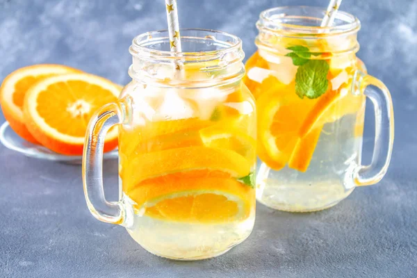 Agua de desintoxicación naranja en frascos de albañil sobre un fondo de hormigón gris. Comida saludable, bebidas . —  Fotos de Stock