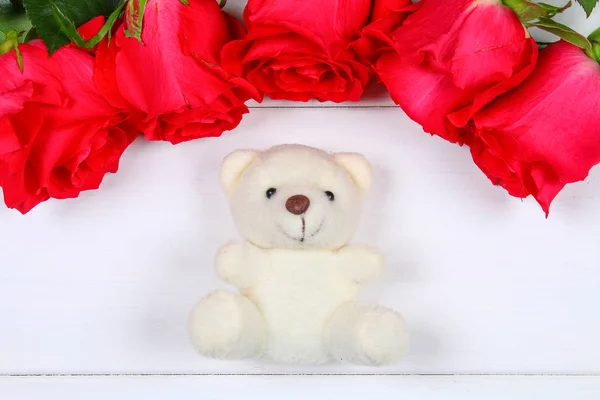 Urso de pelúcia branco cercado por rosas cor-de-rosa em uma mesa de madeira branca. Modelo para 8 de março, Dia das Mães, Dia dos Namorados . — Fotografia de Stock