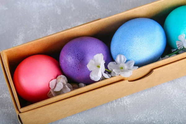 Oeufs de Pâques colorés dans une boîte cadeau sur un fond de béton gris . — Photo