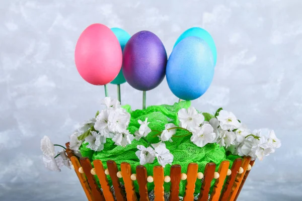 Œufs de Pâques colorés dans un panier sur un fond de béton gris . — Photo