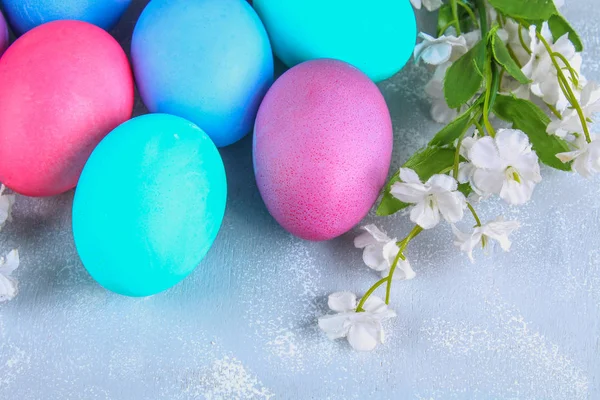 Colored Easter eggs with white flowers on a gray concrete background. — Stock Photo, Image