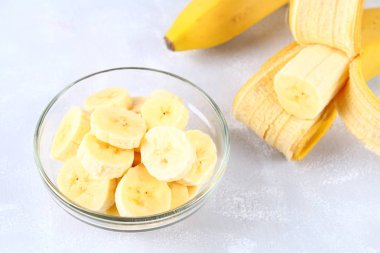 Bütün ve üzerinde gri bir arka plan üzerine bir fincan bir dilim kesilmiş muz.