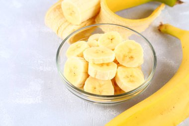 Bütün ve üzerinde gri bir arka plan üzerine bir fincan bir dilim kesilmiş muz.