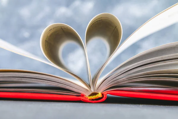 Στις σελίδες του βιβλίου με το κόκκινο κάλυμμα γίνονται με τη μορφή μιας καρδιάς. Η έννοια της ημέρα του Αγίου Βαλεντίνου. — Φωτογραφία Αρχείου