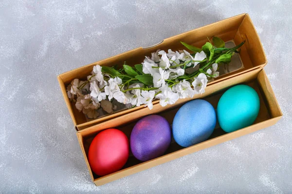 Oeufs de Pâques colorés dans une boîte cadeau sur un fond de béton gris . — Photo