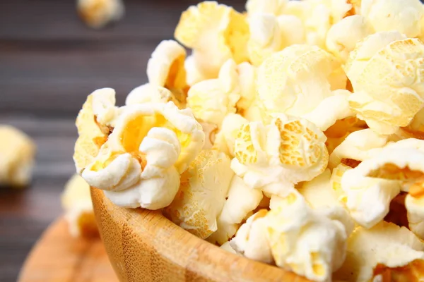 Solené popcorn v dřevěné misce na dřevěný stůl. — Stock fotografie