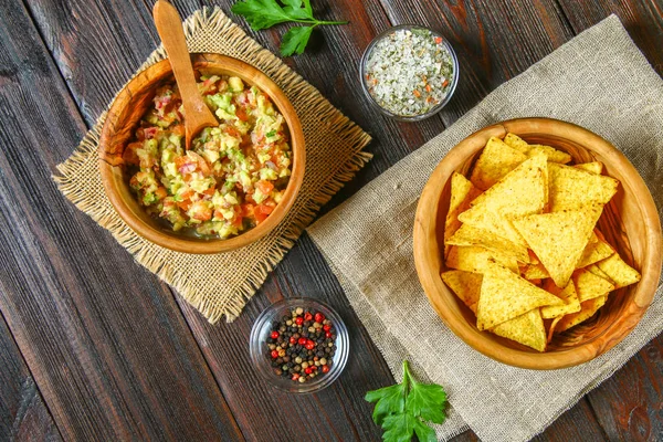 La guacomole es una salsa tradicional mexicana que consiste en aguacate rallado, jugo de limón, cebolla roja, tomates, ajo y chile. Servido con nachos fritos . —  Fotos de Stock