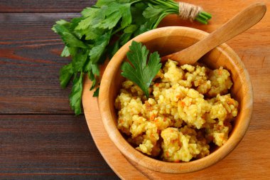 Pirinç pilavı tavuk, baharat ve maydanoz ahşap bir masa üzerinde bir kase ile.